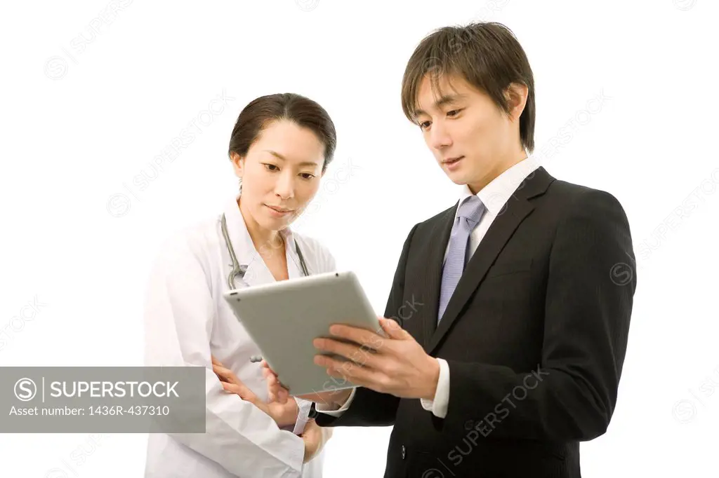 Pharmaceutical sales representative showing tablet computer to female doctor