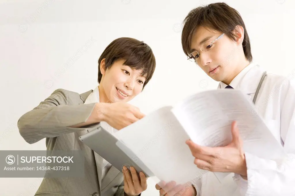 Pharmaceutical sales representative showing file to doctor