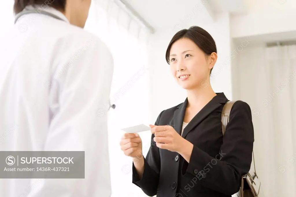 Pharmaceutical sales representative presenting name card to doctor