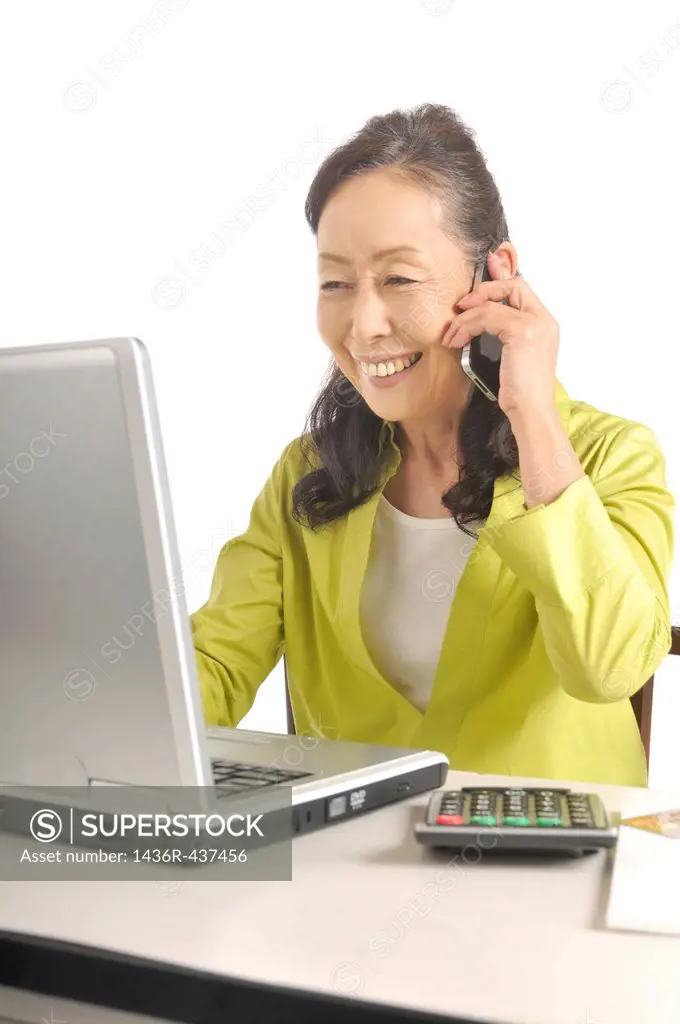 Senior woman using smartphone and laptop