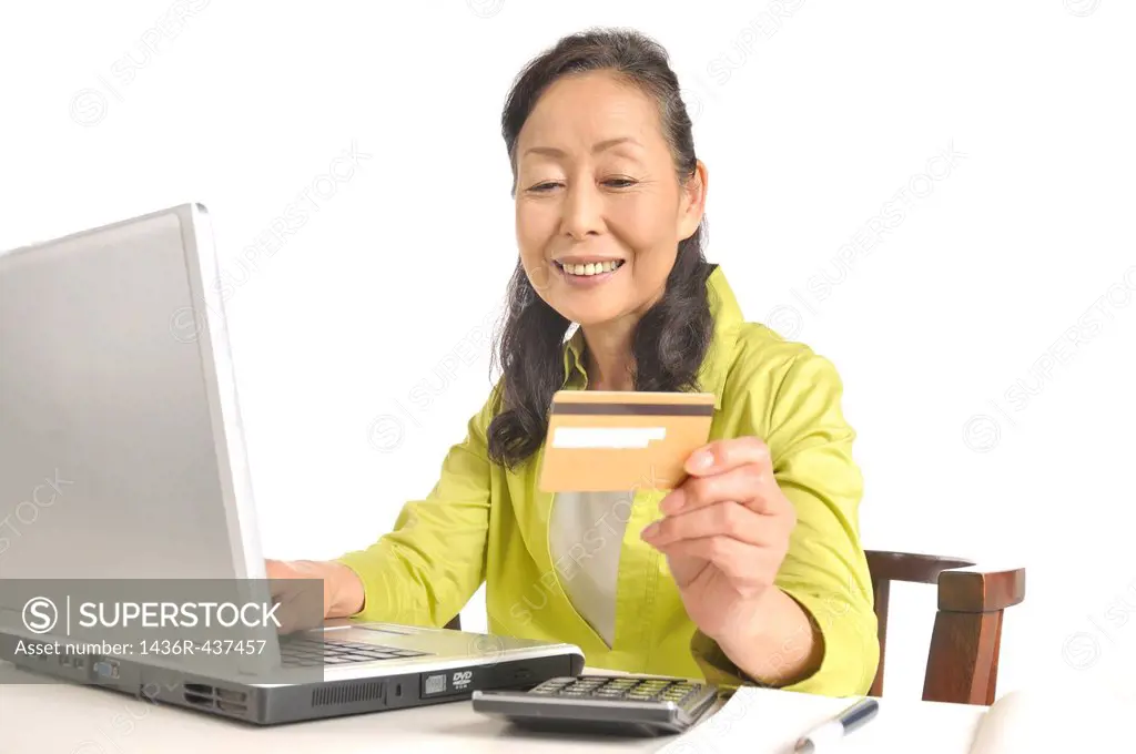 Senior woman holding credit card in front of laptop