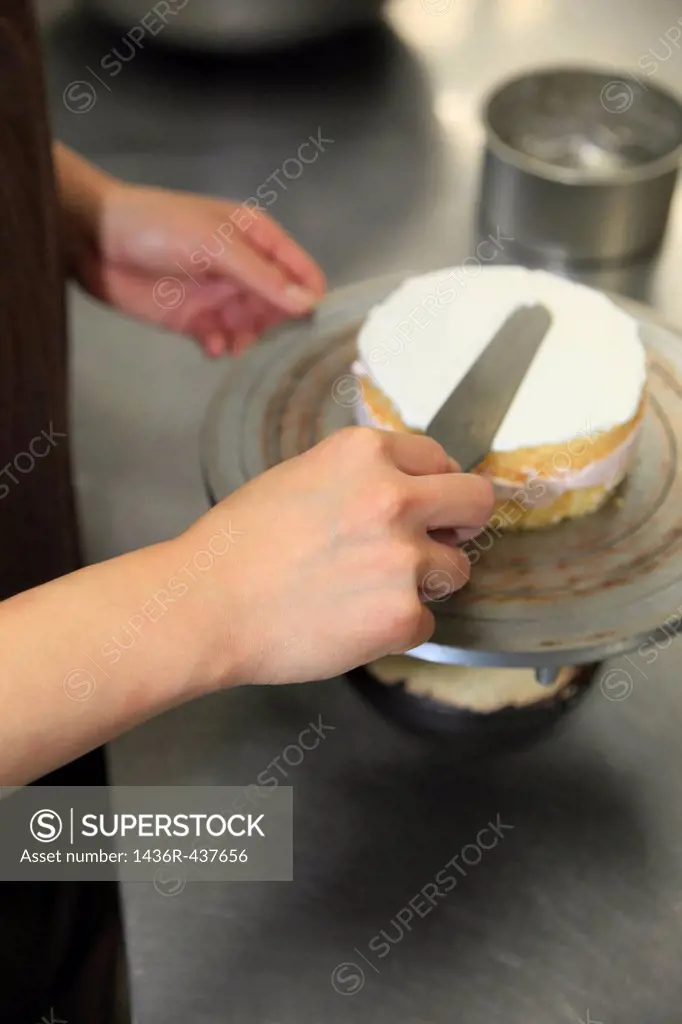 Pastry Chef Spreading Whipped Cream on Cake