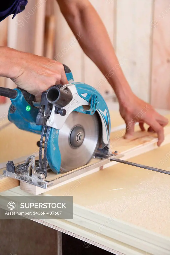 Carpenter Cutting Wood with Electric Saw