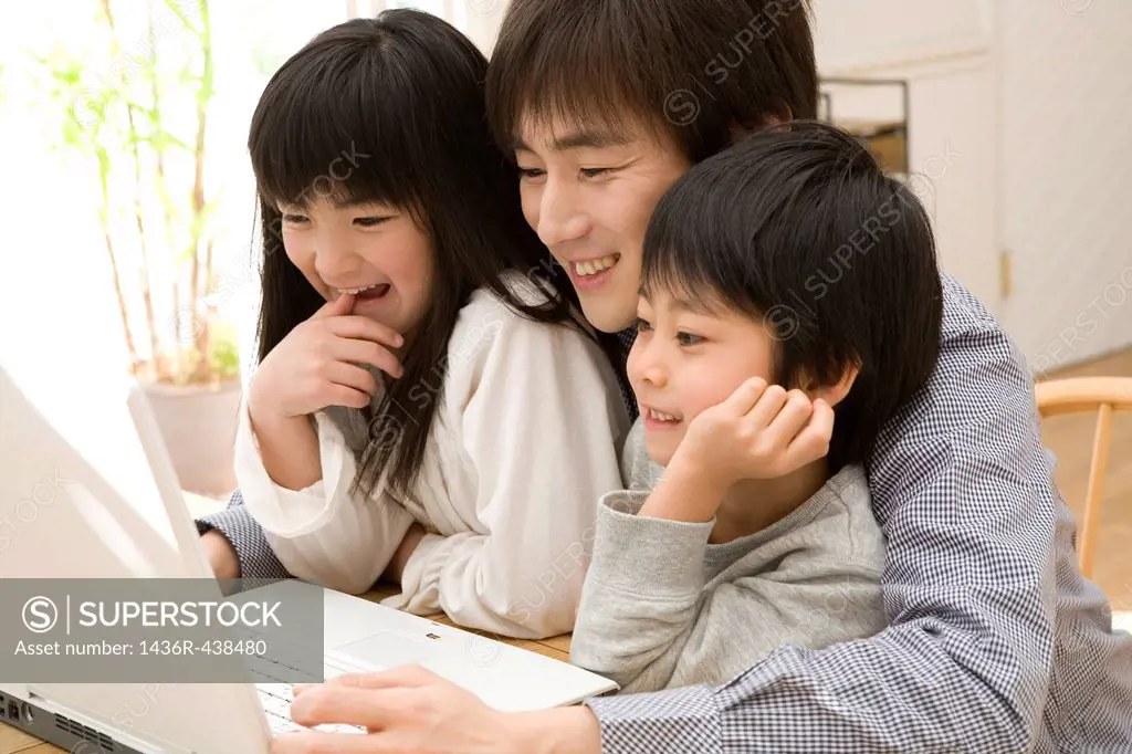 Father using laptop with two children