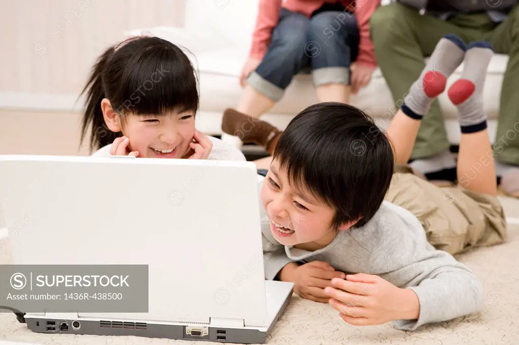 Two children looking laptop and laughing together