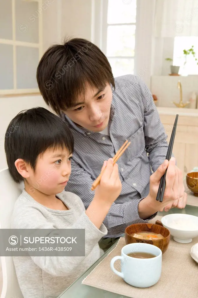 Father teaching son how to use chopsticks