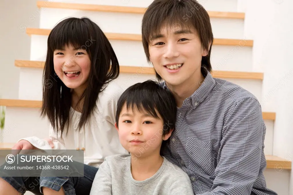 Father and two children sitting and smiling on stairs