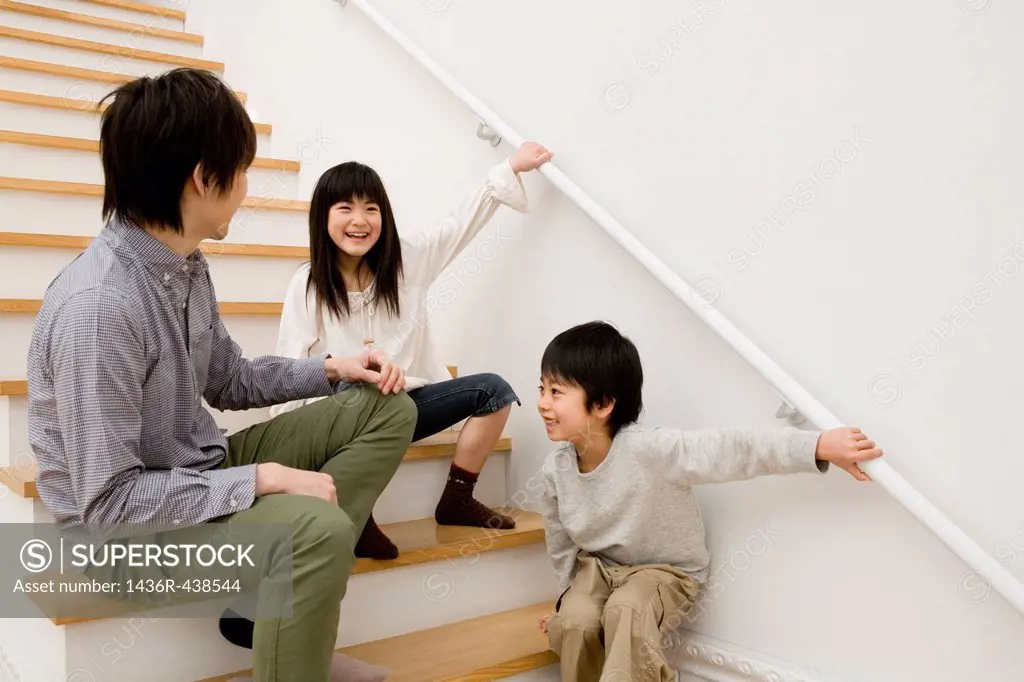 Father playing with two children on stairs