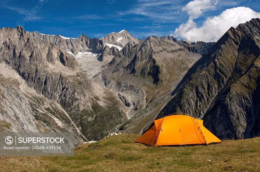 Orange mountain tent above the valley Baltschiedertal, Mt Nesthorn behind, Pennine Alps, Valais, Switzerland