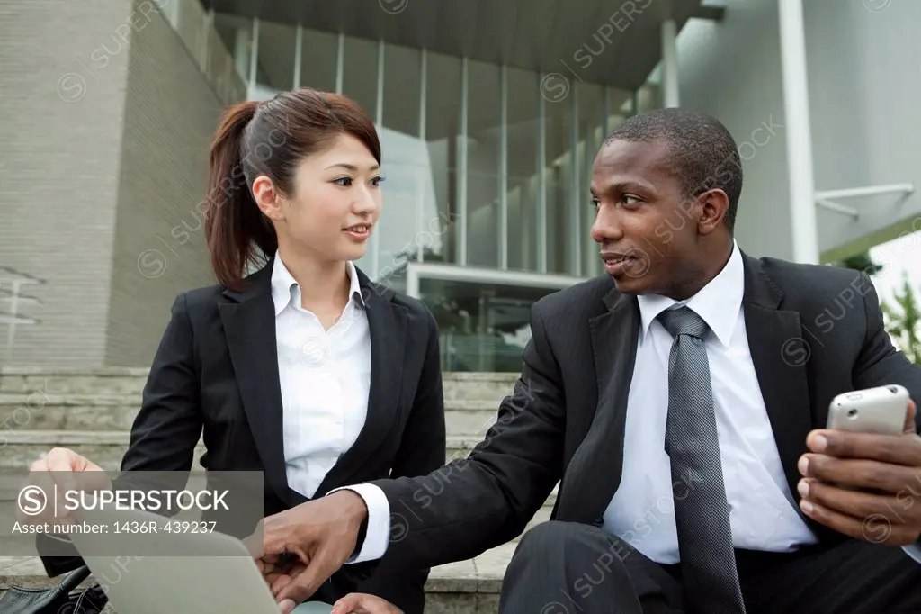 Businessman and businesswoman talking on steps