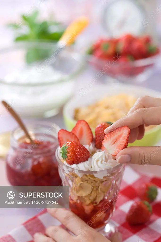 Human Hand Putting Strawberry on Strawberry Parfait