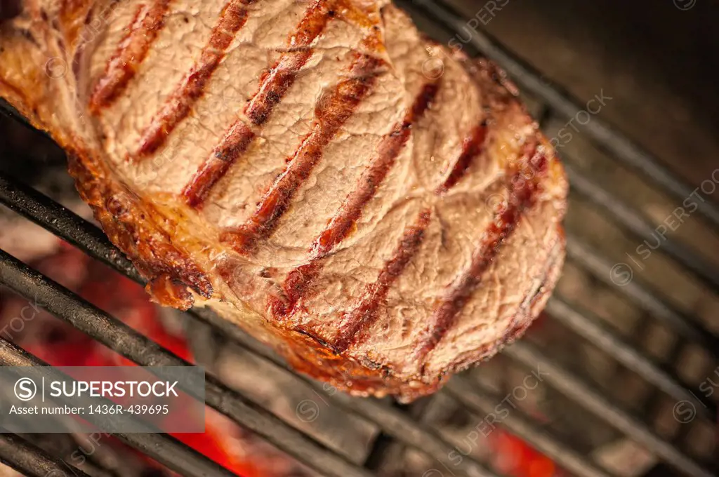 Section of beef ribeye steak on hot barbecue grill