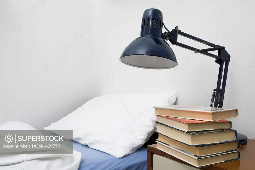 bedside lamp and piled books in bedroom