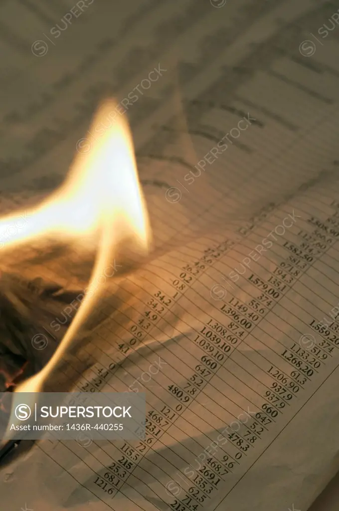 Burning financial newspaper with stock index