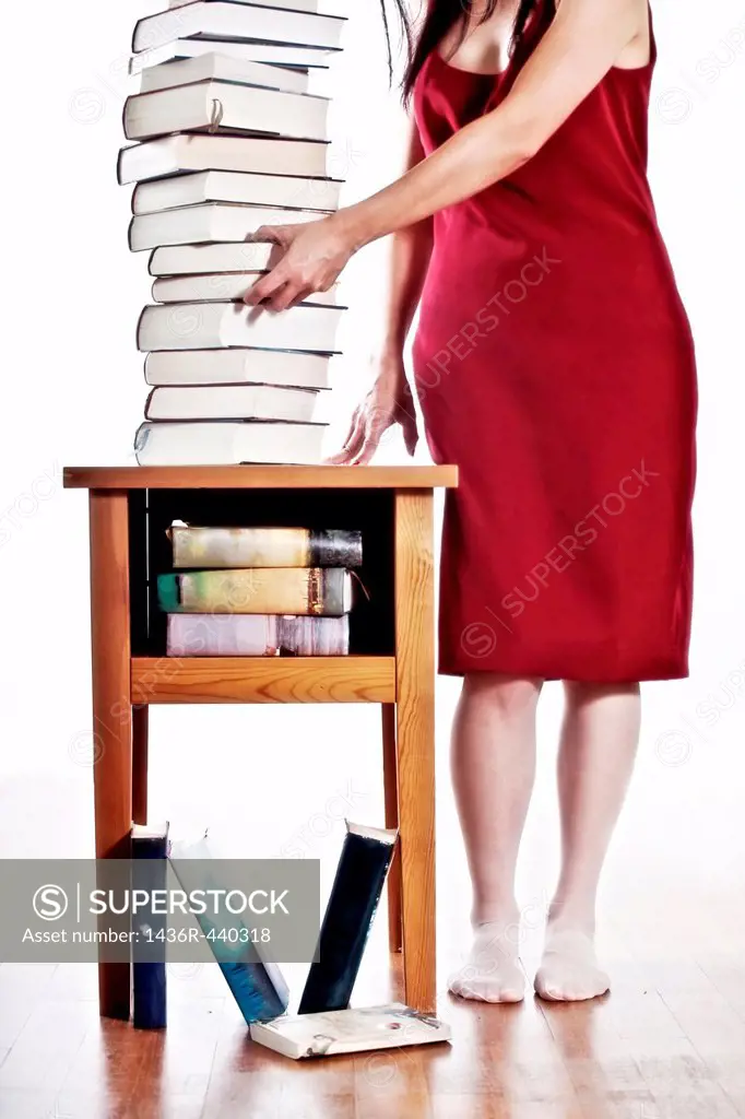 a woman in a red dress standing next to a stack of books