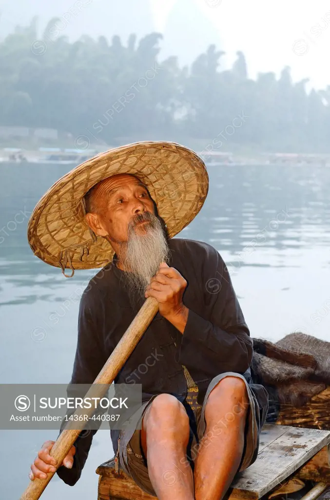 Proud Cormorant fisherman on a bamboo raft on the Li river with Karst mountain peaks China