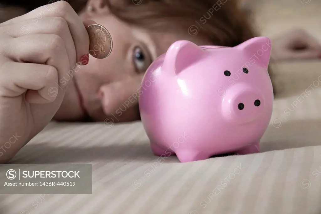 Woman putting an American quarter into a piggy bank