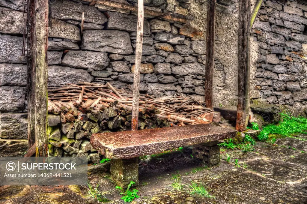Stone bench and firewood close to a stone wall