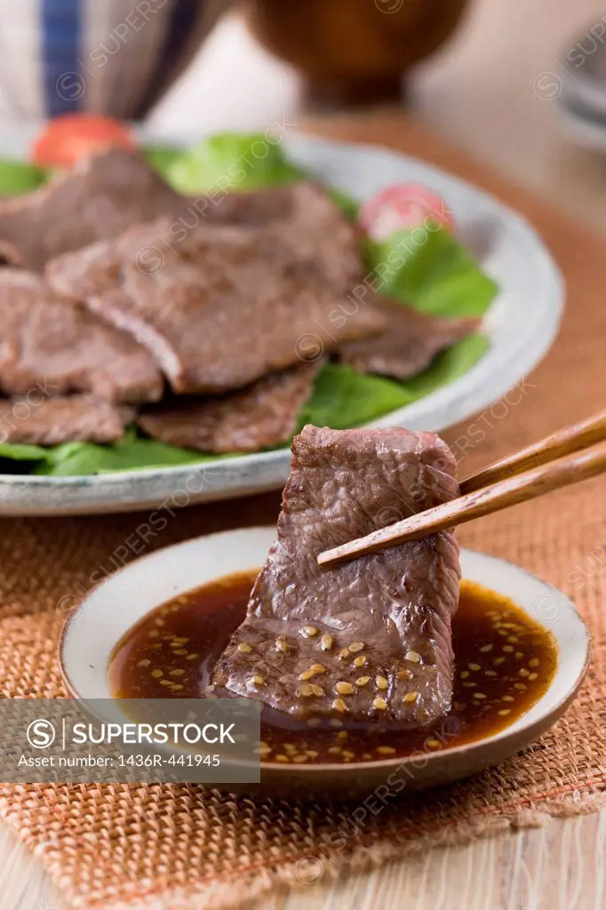 Dipping Broiled Beef into Korean Barbeque Sauce