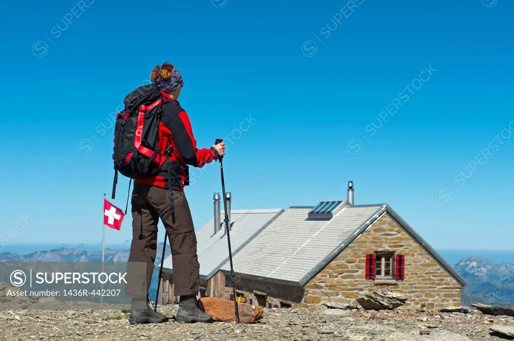 Hiker approaching the mountain hut Wildstrubelhuette of the Swiss Alpin Club SAC, Bernese Alps, Switzerland