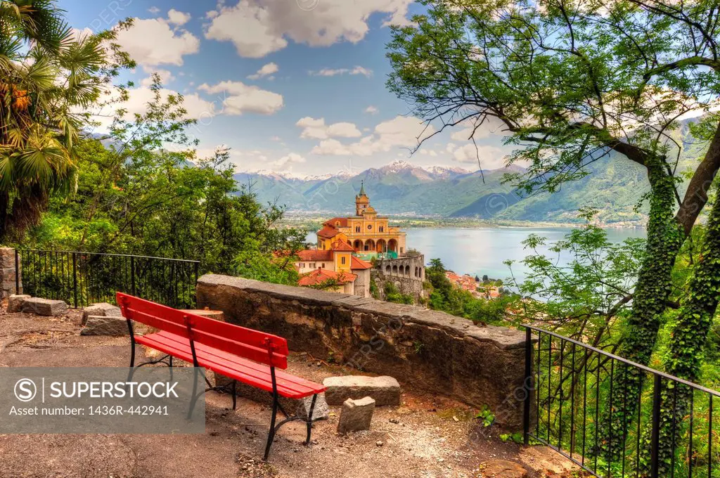 Church on the mountain with a lake and snow-capped mountain and a bench