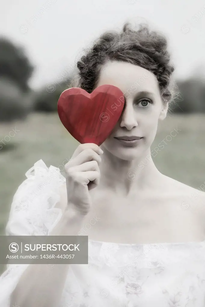 a woman in a period dress is holding a heart