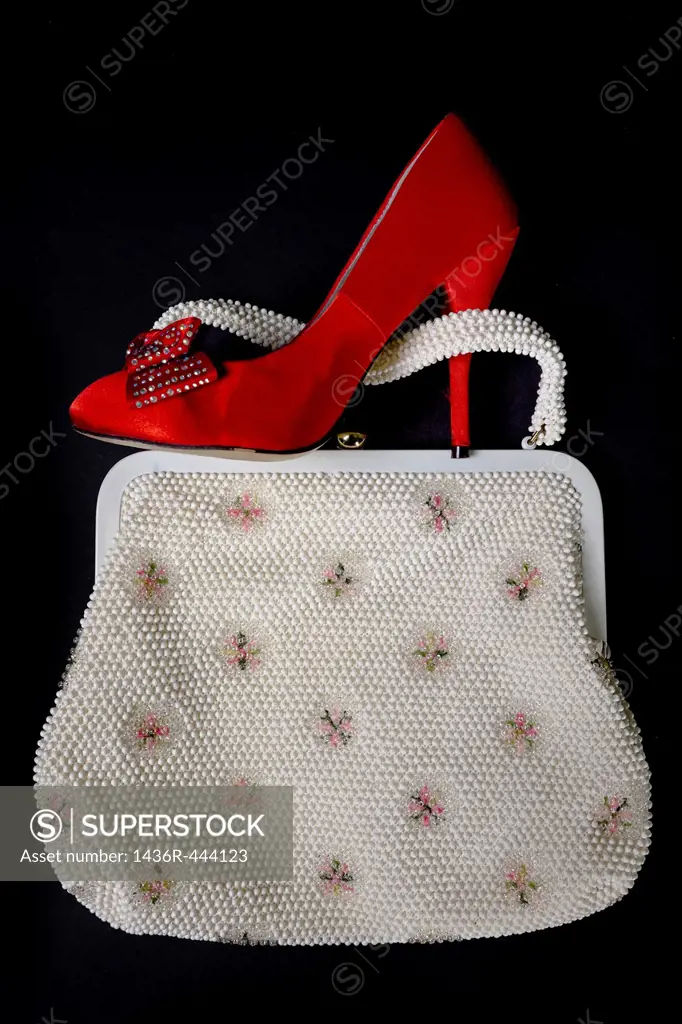 a red shoe with high heels on a vintage handbag