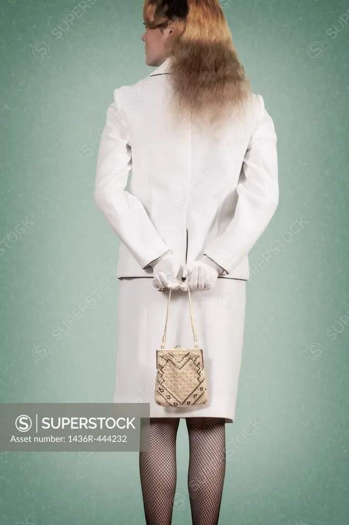 a woman in a vintage skirt suit is holding a handbag