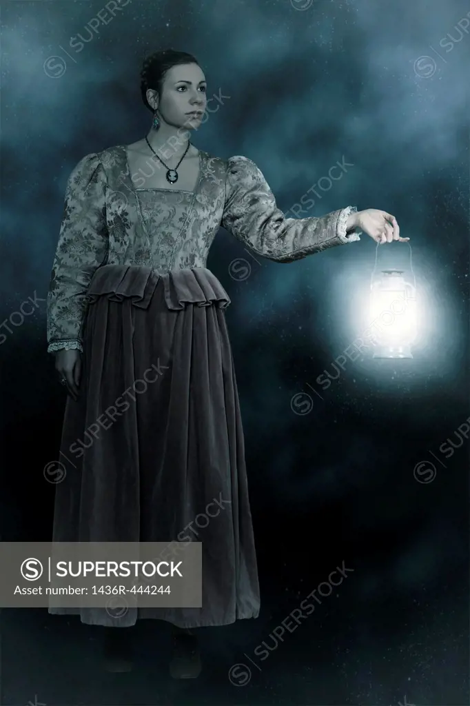 a woman in a victorian dress is holding a lantern in the dark