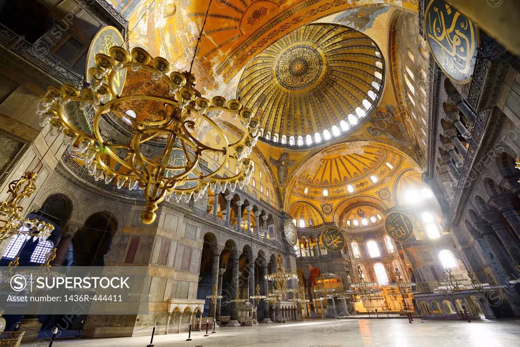 Morning light in an empty Hagia Sophia with chandeliers and golden dome