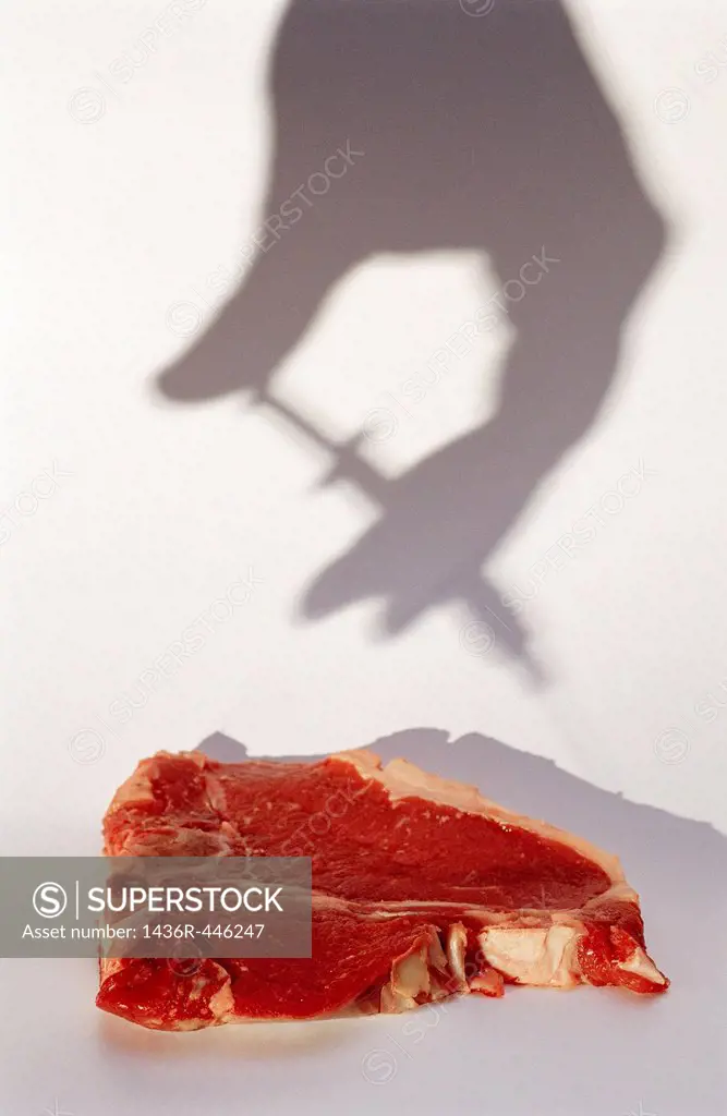 Shadow of hand and syringe above T-bone steak