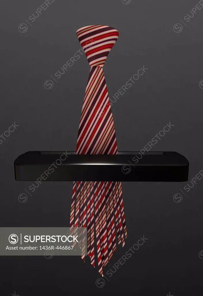 Tie going through paper shredder isolated over gray background representing unemployment issues