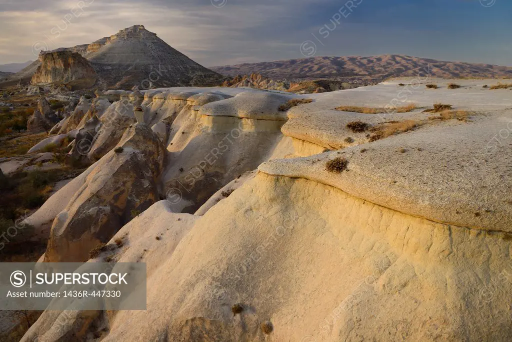 Eroded volcanic tuff lit by evening sun at Pasabag Monks Valley with Avanos beside distant hills Cappadocia Turkey