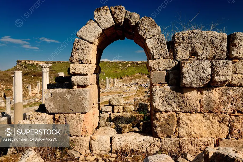View through an arch of the main street colonade with pool and Acropolis at Perge Turkey archaeological site