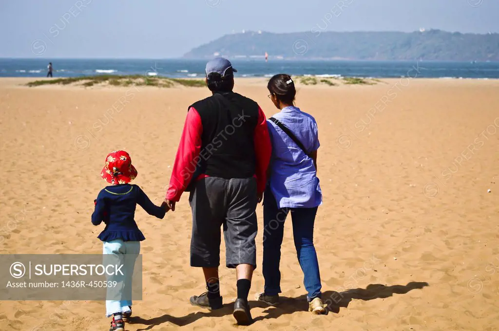 Young family walking on the beach,Goa ,India.