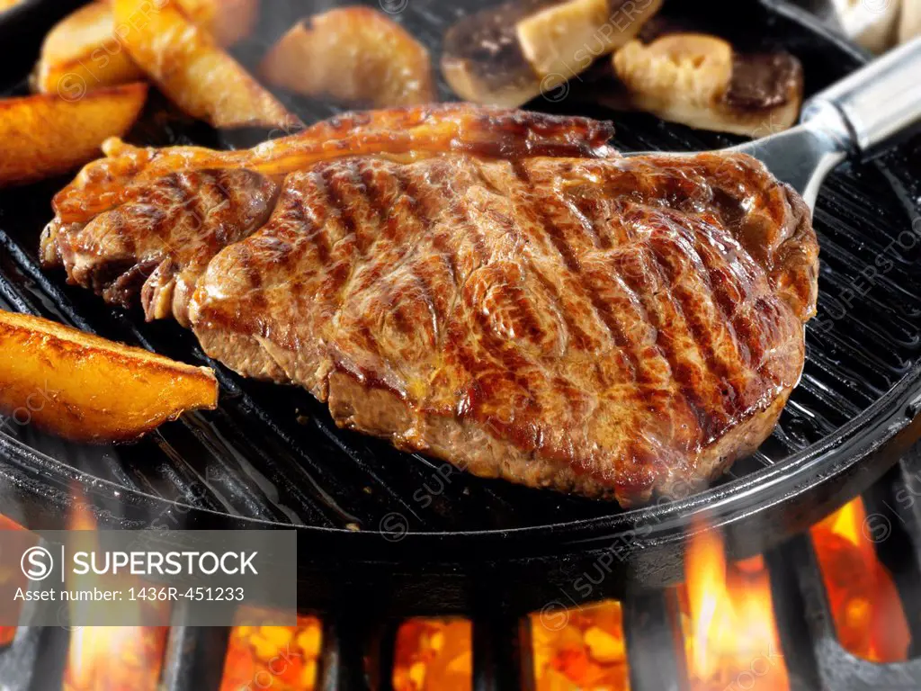 Sirloin beef steaks & chips being pan fried on a bbq. Meat food