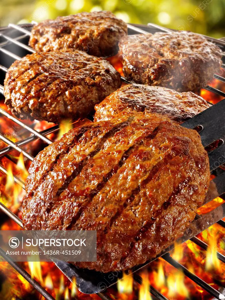 BBQ beef burgers being cooked on a bbq grill.