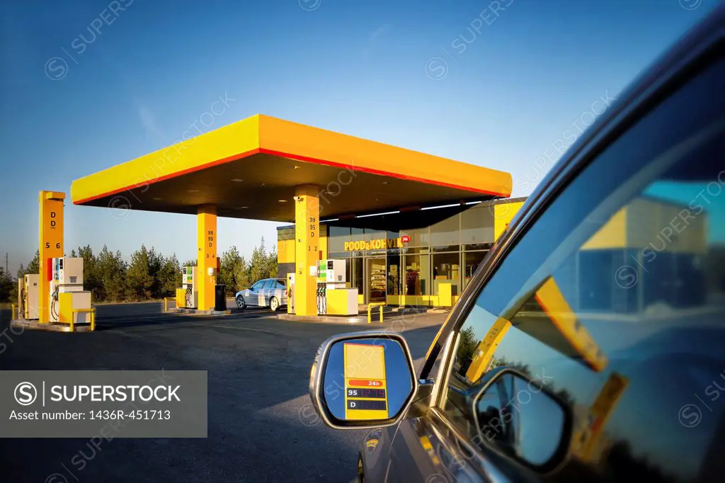 Car in gas station. Reflection on motor vehicle mirror and glass. Convenience store in Estonia.