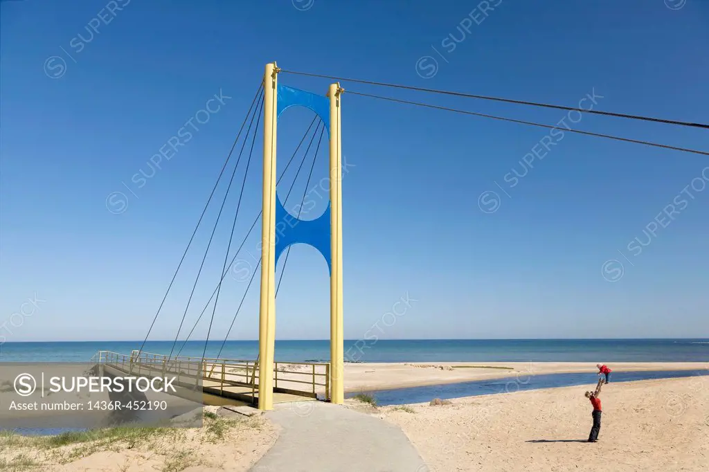 Mother raising kid into the air. Bridge over Vääna river, Estonia. River mouth at Baltic sea.