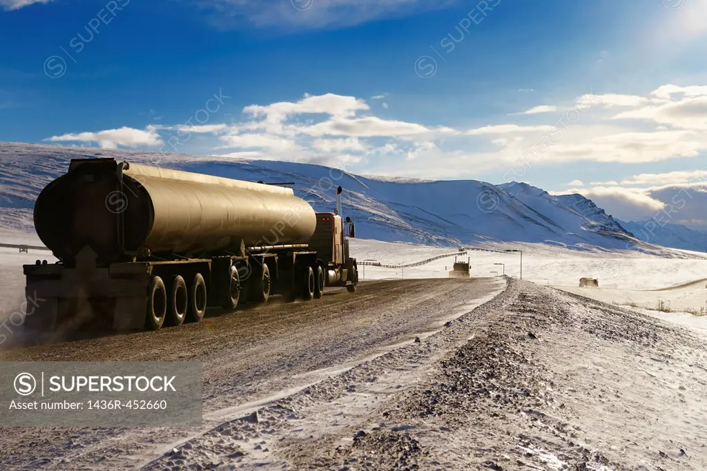 Tankers and trucks driving the Dalton Highway through the Brooks Range mountains Alaska.