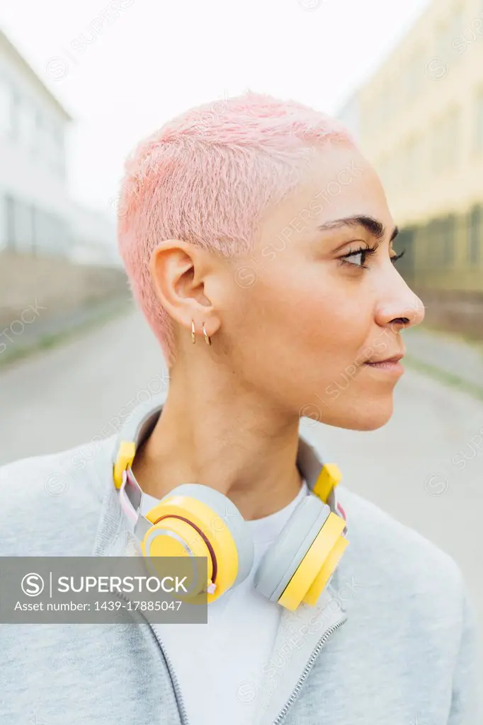 Portrait of young woman with short pink hair, wearing headphones