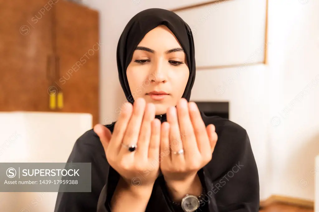 Young muslim woman with hands together during prayer