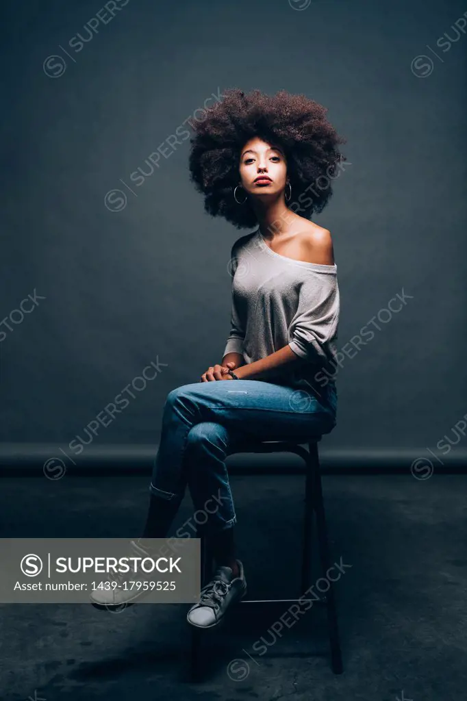 Portrait of a young woman sitting on stool