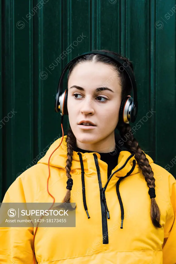 Portrait of teenage girl wearing yellow coat and headphones
