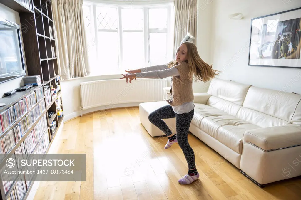 UK, Surrey, Girl dancing in front of TV set in living room