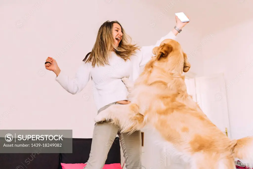 Italy, Young woman playing with dog at home