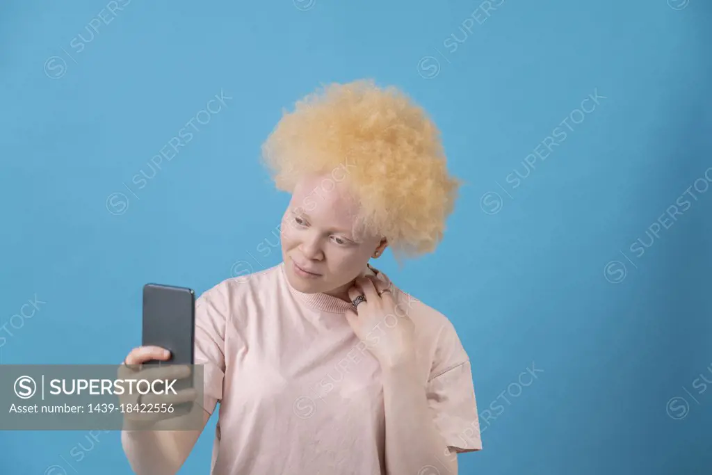 Studio shot of albino woman holding smart phone