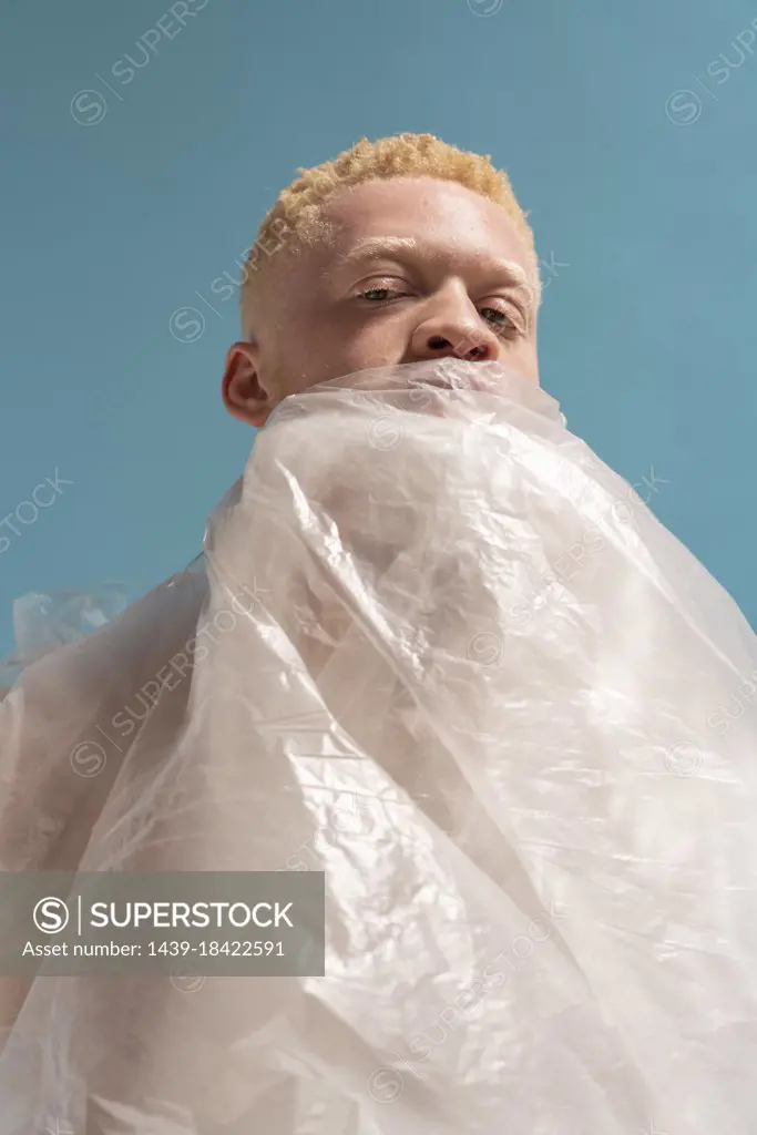 Studio portrait of albino man wrapped in plastic sheet