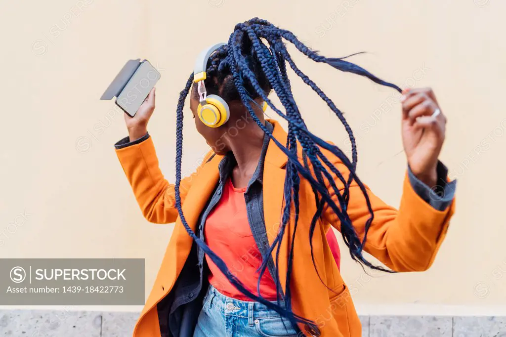 Italy, Milan, Woman with headphones and smart phone dancing outdoors