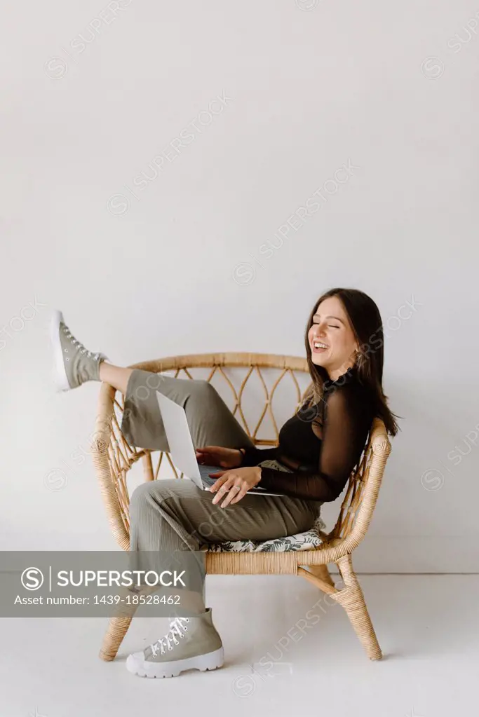 Young woman sitting in chair with laptop